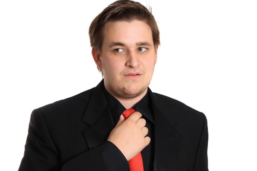 Handsome young businessman loosening or fixing his red tie on a white background