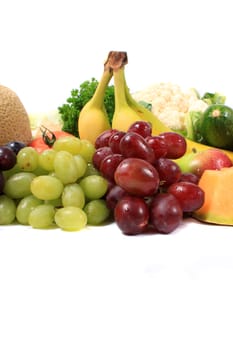 Colorful fresh fruits like grapes, cantaloupe,apples,and bananas on a white background