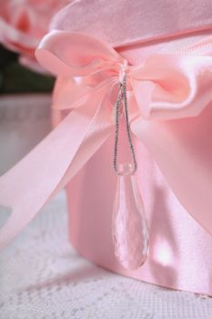 Pretty satin pink bow on box with hanging crystal creating a light reflection