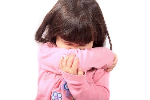 Little sick girl sneezing onto her sleeve because of sickness or allergies