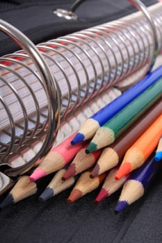 Colorful sharpened  pencil crayons for school  beside  three ring binder 