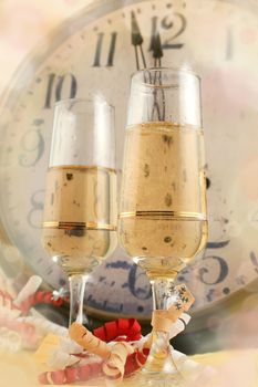 Champagne in glasses with ribbons with new years countdown vintage clock in the background