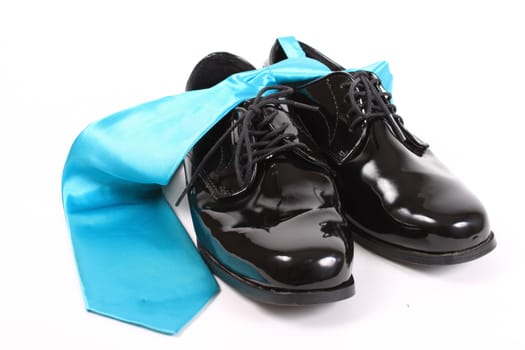 Mens shiny lace up formal black shoes with light blue tie on a white background