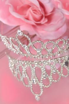 Mirror reflection of a beautiful diamond or rhinestone crown for a beauty pageant or wedding, with pink roses in the background