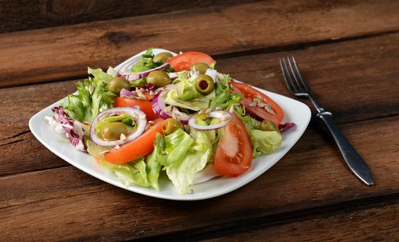 Salad with tomatoes and olives on wooden background
