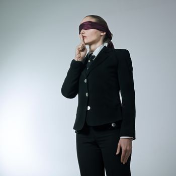 studio shot portrait young blindfold business woman hushing finger on lips