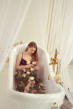 Girl in underwear lying in the bathroom with roses without water