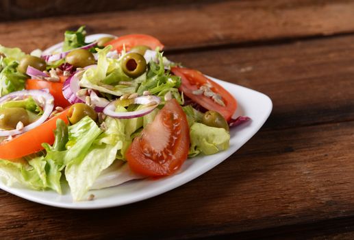 Salad with tomatoes and olives on wooden background