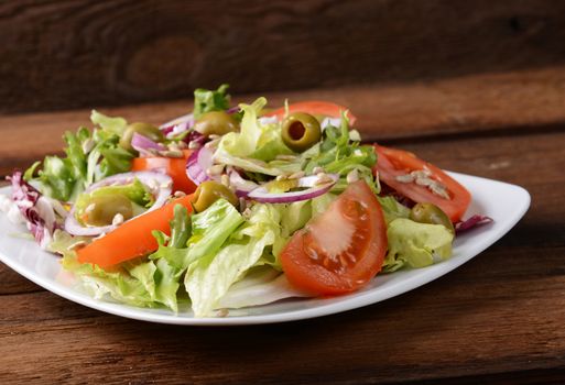 Salad with tomatoes and olives on wooden background