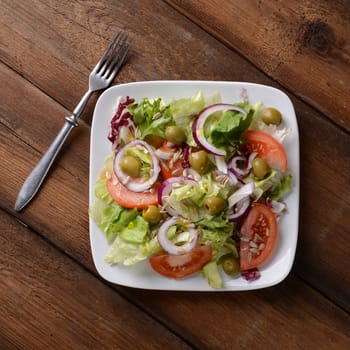 Salad with tomatoes and olives on wooden background