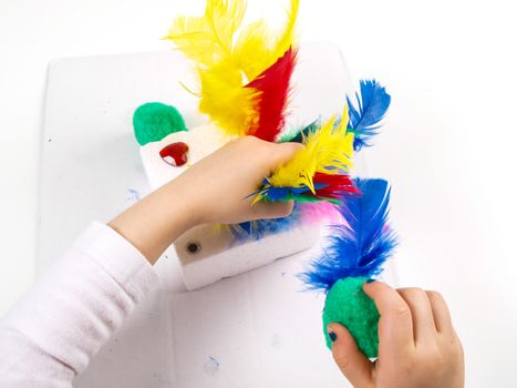 Little girls hands playing with colorful feathers, creating Easter decoration