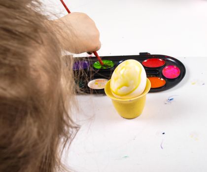 Little girls hands playing with colorful paint, creating Easter decoration