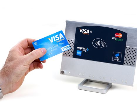 Aachen, Germany - August 05, 2012: Studioshot of payment action with the visa paywave credit card in front of a NFC terminal wich accepts visa, mastercard, american express and girogo contactless payments.