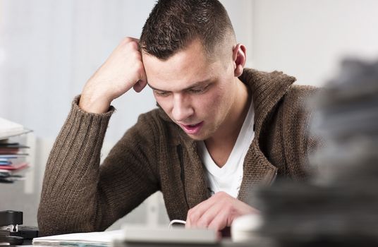 Young handsome businessman reading documents at office. Horizontal shot