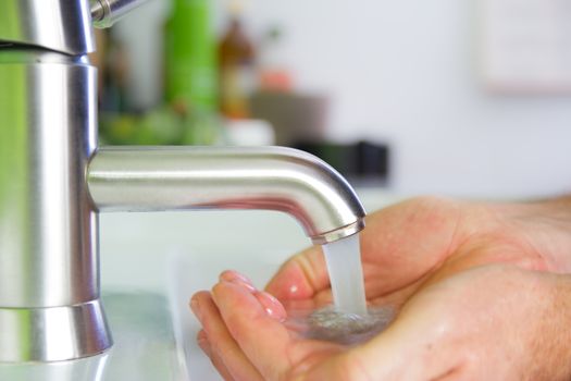 holding hand under sparkling fresh water out of the faucet