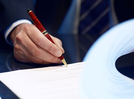 Businessman sitting at shiny office desk signing a contract with noble classic pen 