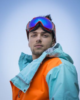 Friendly attractive skier or snowboarder against blue sky looking at camera