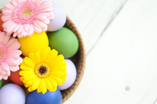 Easter eggs inside a wicker basket with daisies