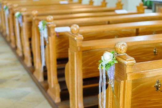 Wooden church bench with flower decoration for a wedding ceremony