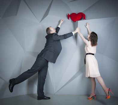 man and woman reaching for red heart