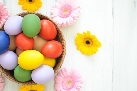 Easter eggs inside a wicker basket with daisies