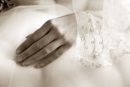 Hands of the bride on a background of a wedding dress