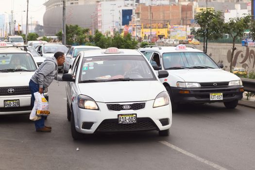LIMA, PERU - JULY 21, 2013: Unidentified man asking a taxi for the fare on Av. Paseo de la Republica in the city center on July 21, 2013 in Lima, Peru. In Lima, taxi fares are agreed upon beforehand, fares are not standardized.