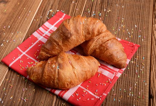 Fresh baked croissants on wooden background