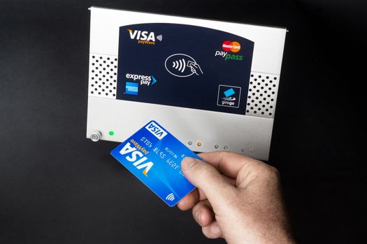 Aachen, Germany - August 05, 2012: Studioshot of payment action with the Visa paywave credit card in front of a NFC terminal wich accepts visa, mastercard, american express and girogo contactless payments.