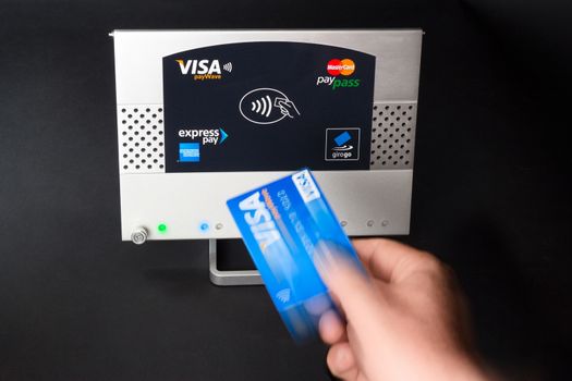 Aachen, Germany - August 05, 2012: Studioshot of payment action with the Visa paywave credit card in front of a NFC terminal wich accepts visa, mastercard, american express and girogo contactless payments.