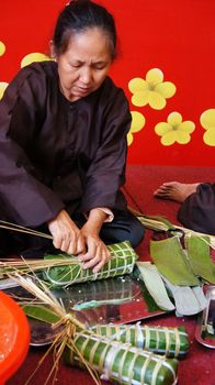 HO CHI MINH CITY, VIET NAM- JAN 15: Senior people make traditional cake for New Year occasion, the cake cover by green bananna leaf in Ho Chi Minh, Vietnam on Jan 15, 2013