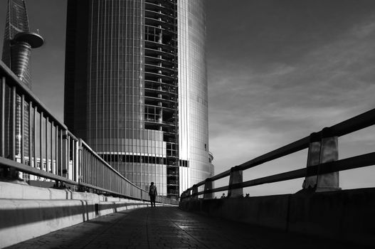 silhouette 's lonely people walking on the way to highrise buidling of modern city, the person become tiny with high building