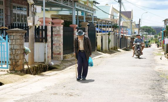 DA LAT, VIET NAM- SEPTEMBER 5: The white beard old man with stick in hand walking on the street in Dalat, Viet Nam on September 5, 2013          