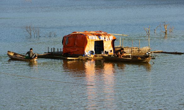 DAKLAK, VIET NAM- DEC 31:Tranquil,calm scene at evening on fishing village, small thatched house and boat tint by golden light, Daklak, Vietnam, Dec 31,2013                                        