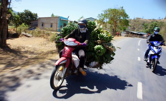 DAK LAK, VIET NAM- FEBRUARY 18: People transport fruit by motorcycle on road in Dak lak, Viet Nam on February 18, 2013