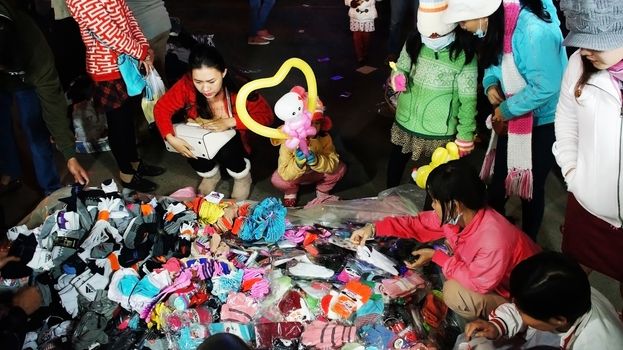 DA LAT, VIET NAM, ASIA- DEC 29: Activity of traveler (tourist) in outdoor market at night, people enjoy cold weather and shopping stocking, gloves hand in Dalat, VietNam, Asia, Dec 29, 2013