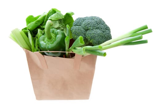 Brown paper bag with healthy green vegetables over a white background 