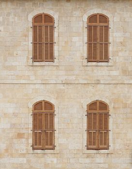 Wall of the old building with closed windows covered by wooden blinds