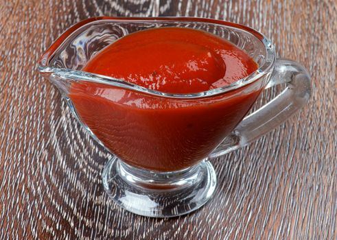 Ketchup in Glass Gravy Boat isolated on Wooden background