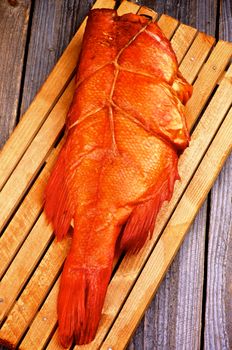 Delicious Smoked Red Snapper Fish on Cutting Board closeup on Rustic Wooden background