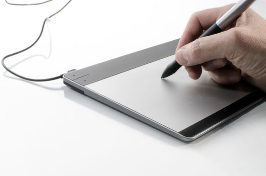 A hand holding a pen against a computer touch pad.