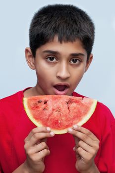 an handsome indian kid savoring a watermelon, a healthy diet