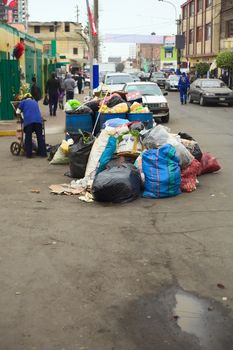 LIMA, PERU - JULY 27, 2013: Pile of garbage waiting to be picked up by the garbage truck at the entrance of the market Mercado No. 2 de Surquillo in the street Calle Junin on July 27, 2013 in Surquillo, Lima, Peru. In Lima, garbage is being picked up every day usually in the evenings and is organised by the districts.