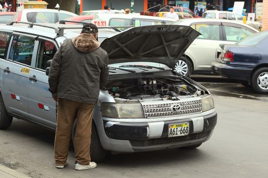 LIMA, PERU - JULY 21, 2013: Unidentified taxi driver checking the engine of his car on July 21, 2013 in Lima, Peru. 