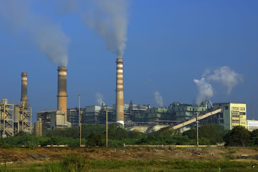 Factory emitting smoke on a bright sunny day