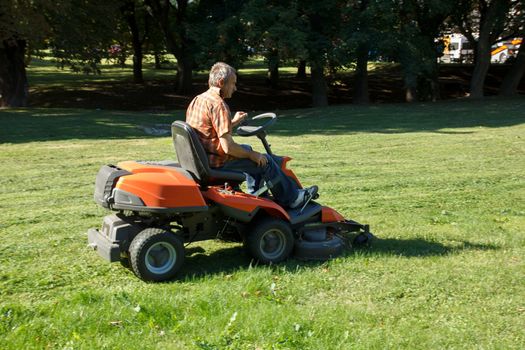 man on tractor mow the grass in the city park