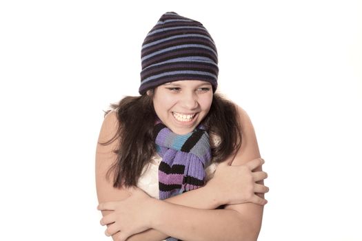 Young pretty pre teen brunette girl smiling hugging herself as if cold on a white background 