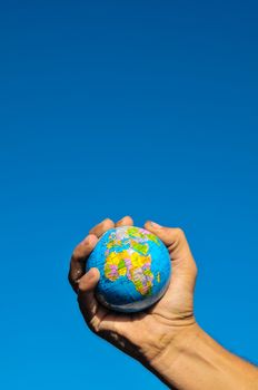 Vintage Old Globe Earth and Human Hand over a Blue Sky