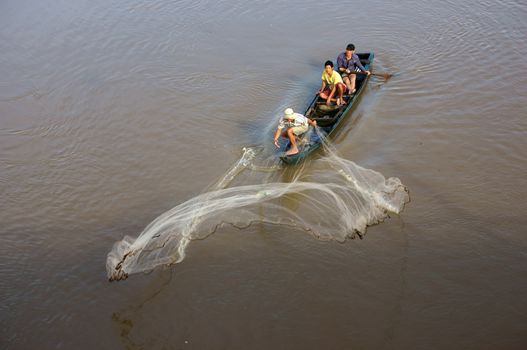 AN GIANG, VIET NAM- NOV 13: Nice, unique posture of fisherman when he cast a net from wooden boat on river in An Giang, Viet Nam on Nov 13, 2013