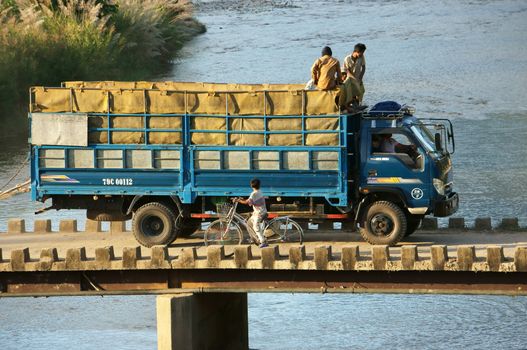 KHANH HOA, VIET NAM- FEBRUARY 5: Truck and bicycle moving on the bridge across stream in unsafe situation, Khanh Hoa, Viet Nam on February 5, 2013                               